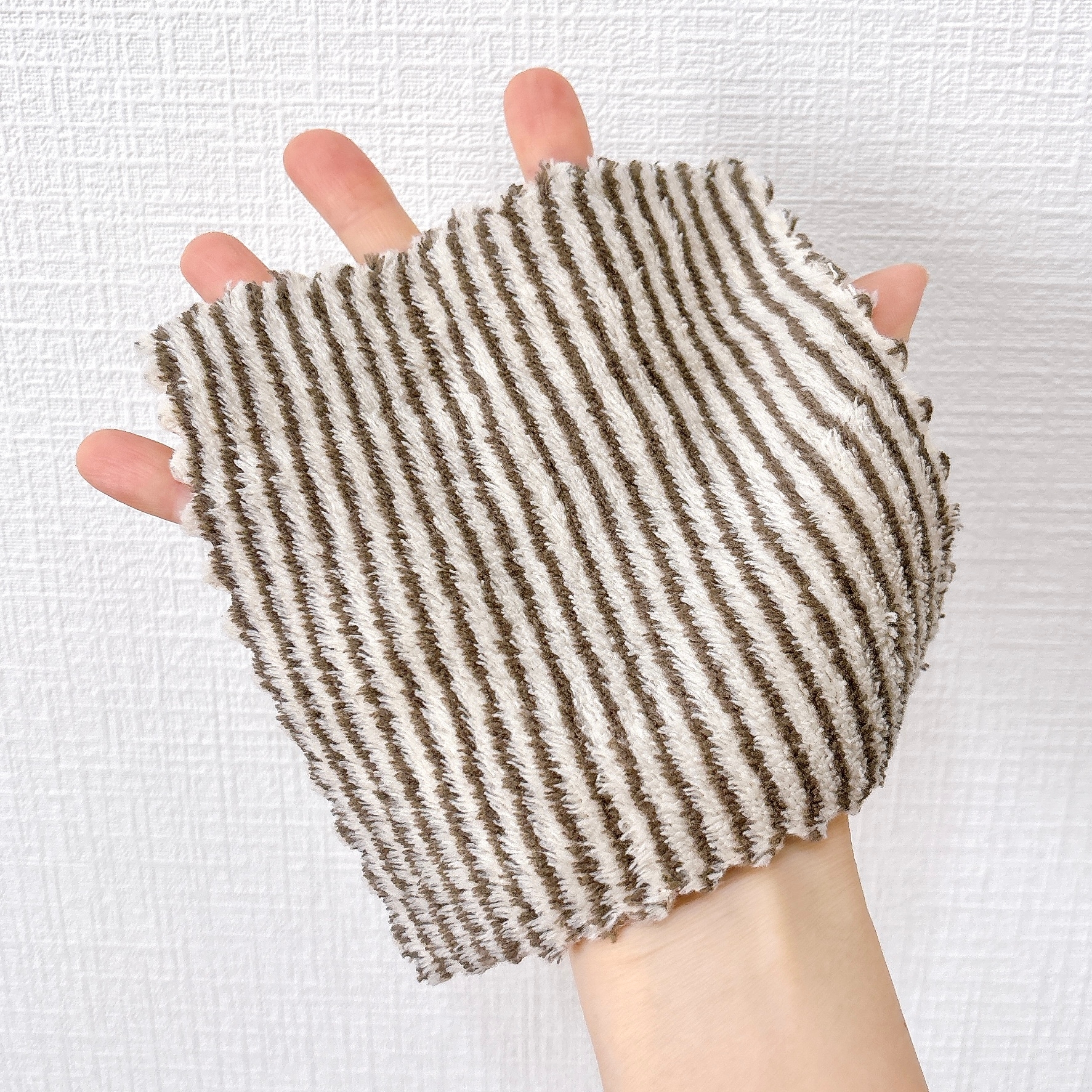 手のひらに茶色と白のストライプの布が乗っている様子。