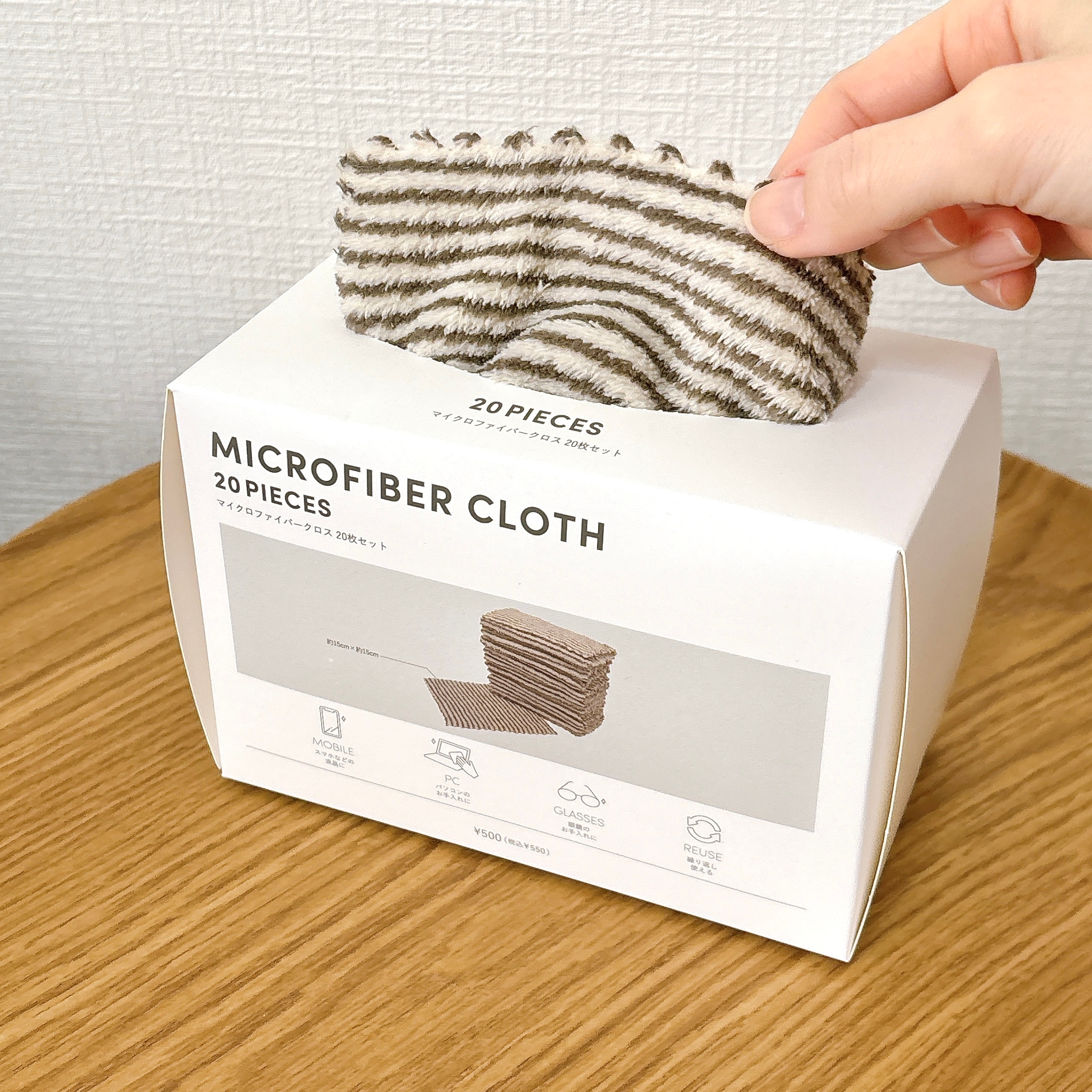 マイクロファイバークロス20枚入りが箱に収納され、手で1枚取り出している様子。洗浄用に最適。