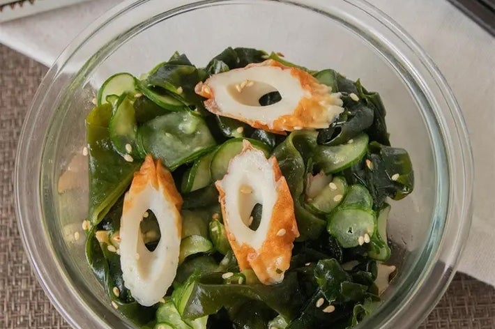 ガラスのボウルにわかめときゅうりの和え物、ちくわのスライスがトッピングされた料理。