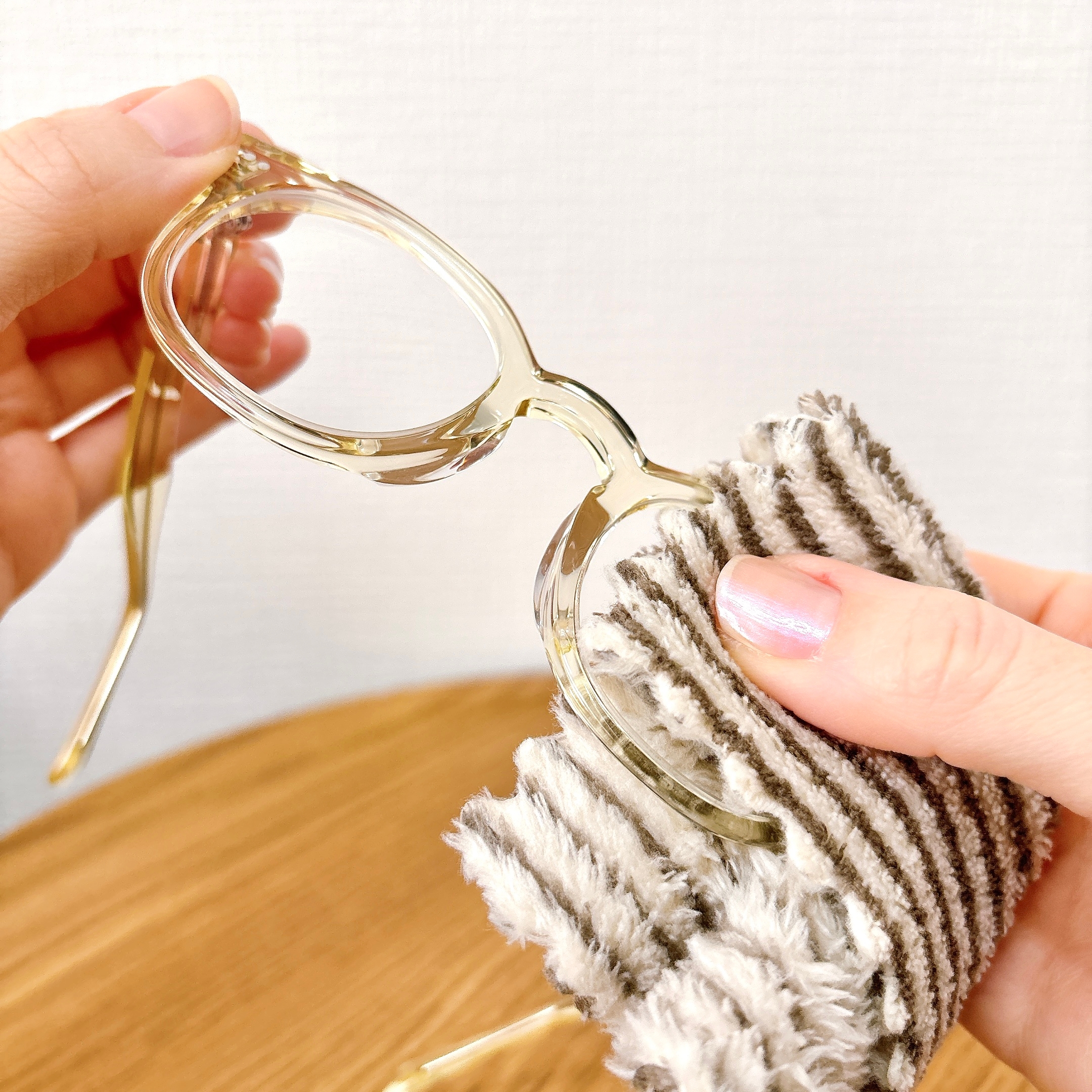 人が布で眼鏡を丁寧に拭いている様子。