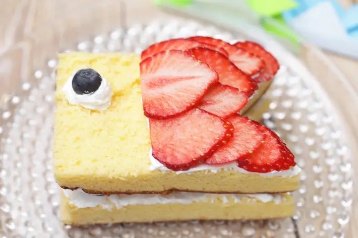 ケーキの上にスライスしたイチゴとクリームが載った魚の形のデザート。