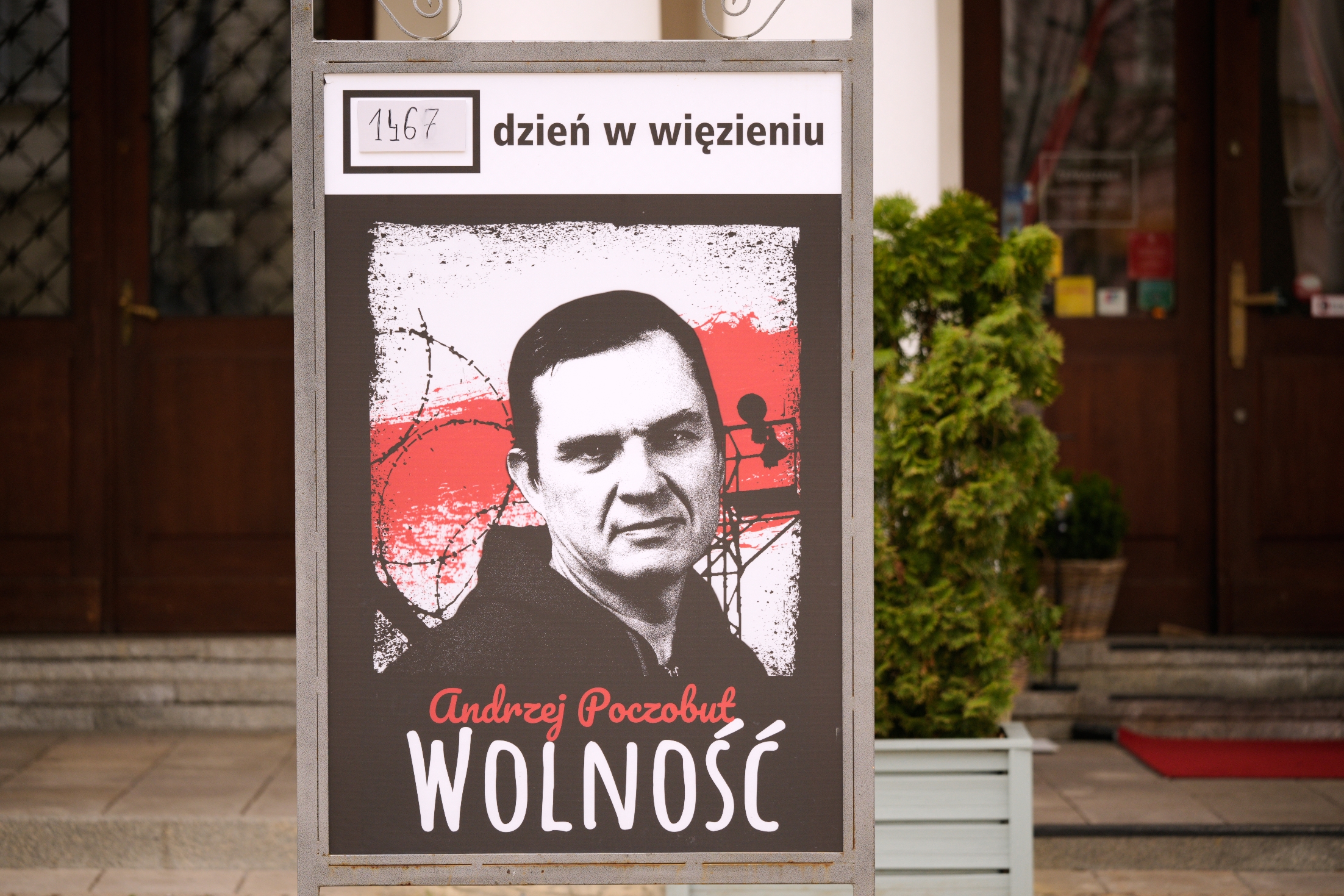 Poster of Andrzej Poczobut with barbed wire and "Freedom" in Polish, marking 1467 days of imprisonment, outside a building