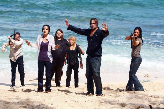 Characters in "Lost stand on a beach, looking outward with concerned expressions, hands raised