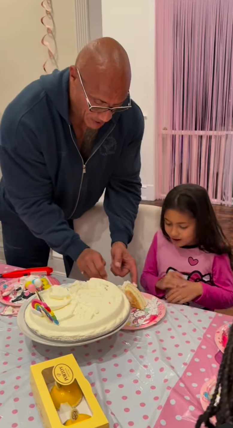 Dwayne Johnson cuts a birthday cake with a child at a decorated table
