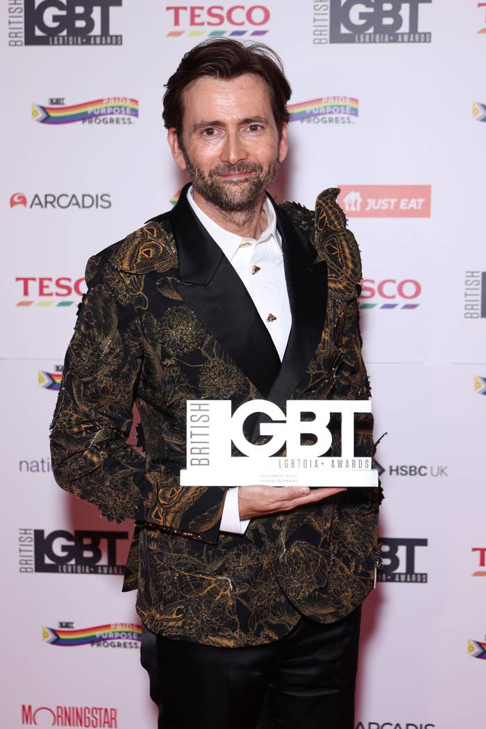 Man in patterned jacket holding an award at British LGBT Awards red carpet event