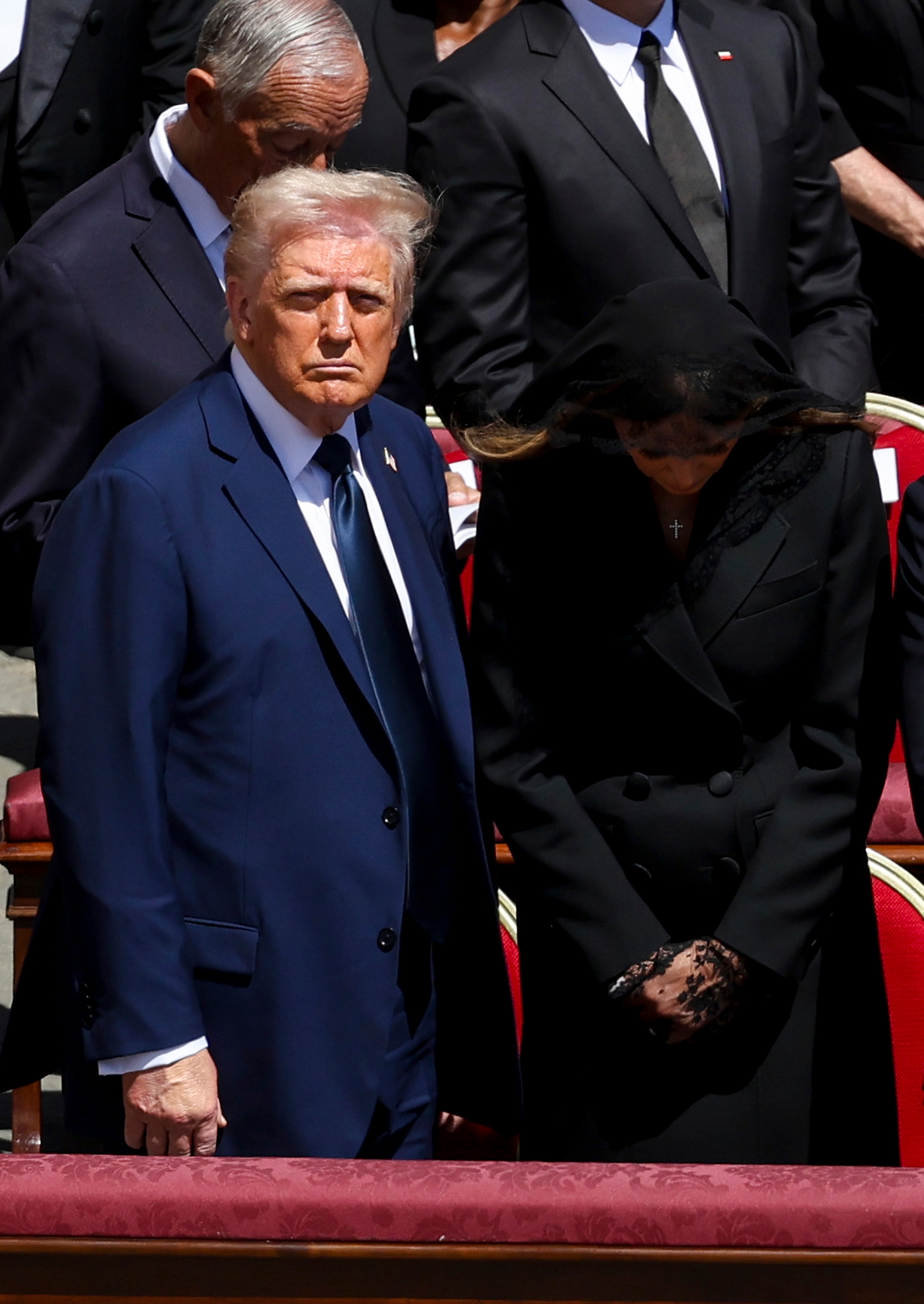 Two individuals at a formal event. The man wears a suit, the woman a veil and dress