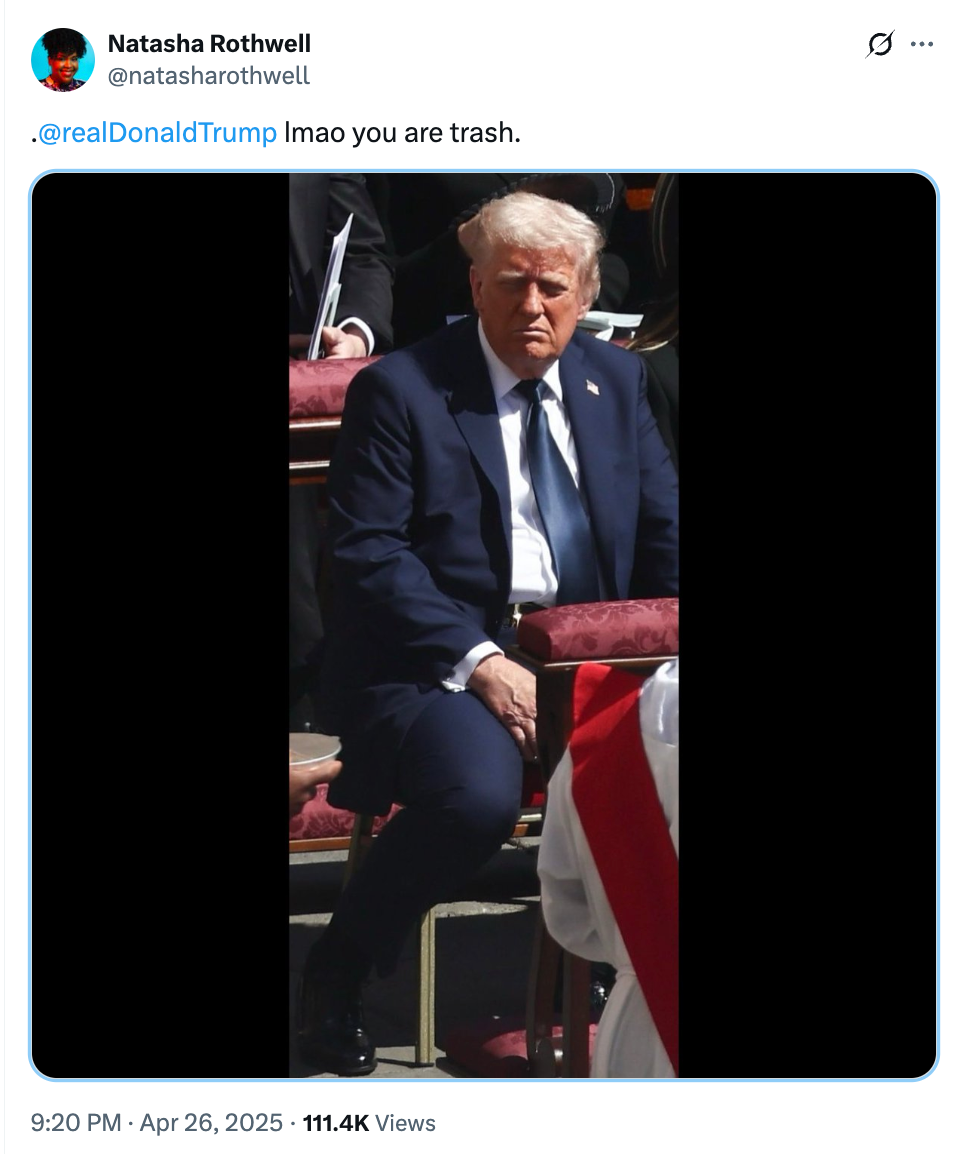 A person in a suit is seated at an outdoor event. A tweet above calls out a public figure