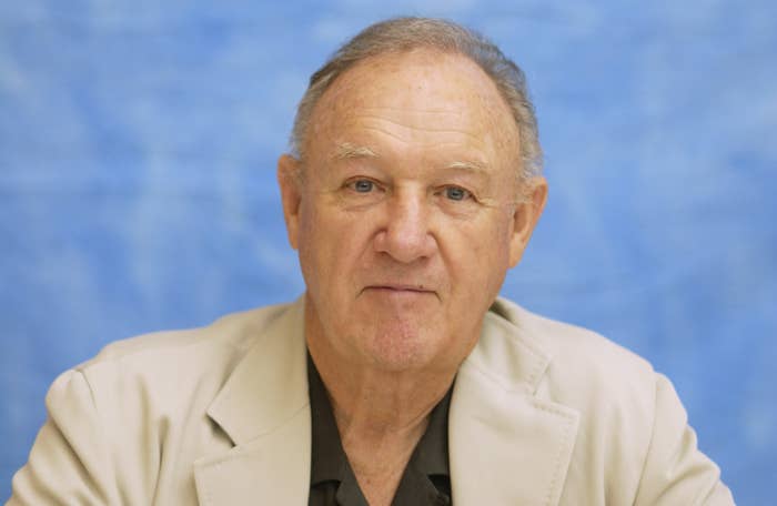An older man in a beige suit jacket and dark shirt poses against a plain backdrop, likely for a news article or interview feature