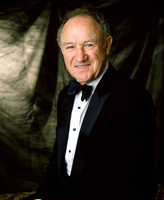 Person in a formal black tuxedo and bow tie, smiling, against a dark background
