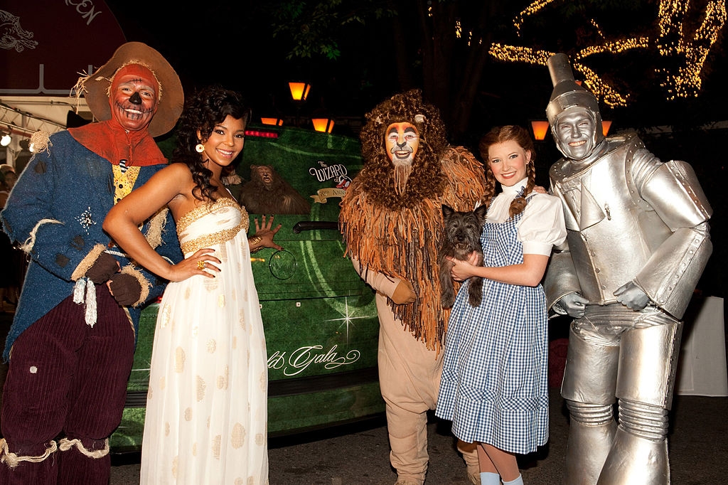 Group dressed as "The Wizard of Oz" characters at an event; includes Scarecrow, Tin Man, Dorothy, Lion, and Glinda in a white gown