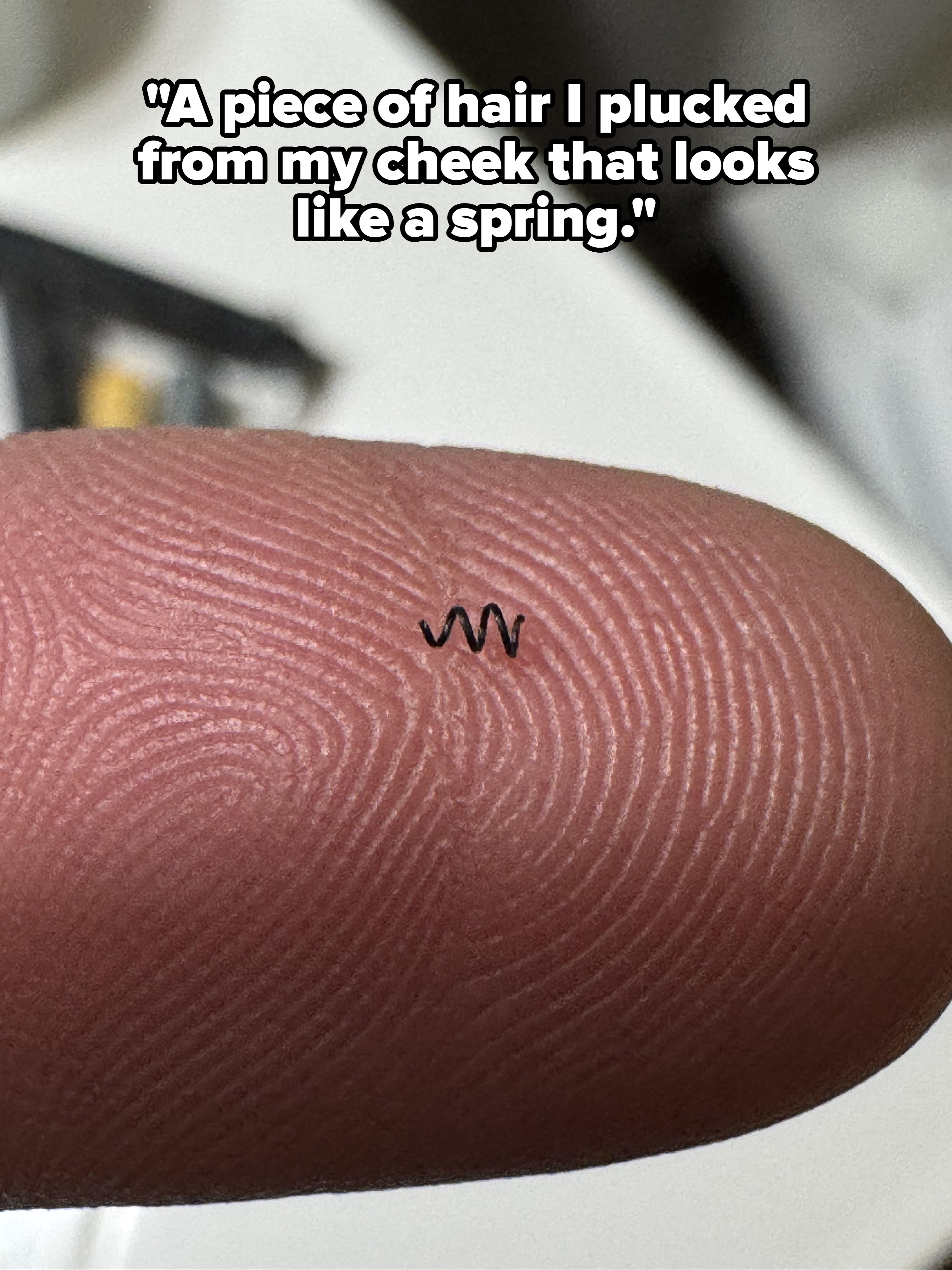 Tiny tattoo of wavy lines on a fingertip, highlighting the detail of the fingerprint ridges