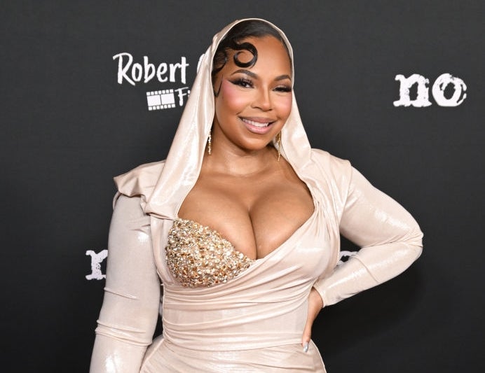 Person poses on the red carpet in a fitted gown with a sequined top and high slit, smiling confidently