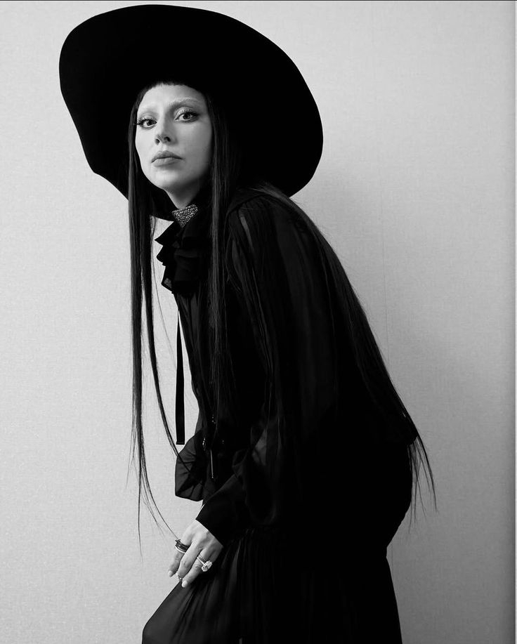 Persona con sombrero de ala ancha y vestido largo, mirando a la cámara, en el contexto de un artículo musical