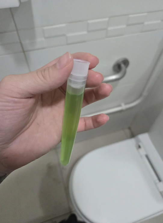 Hand holding a test tube with green liquid
