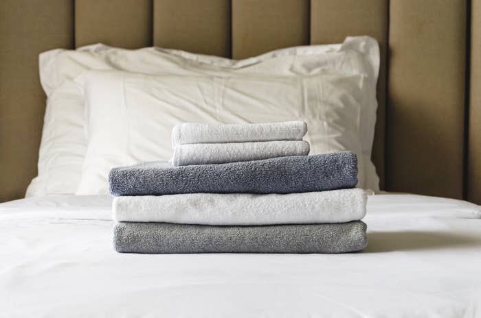 Stack of neatly folded towels on a made bed, creating a sense of comfort and tidiness