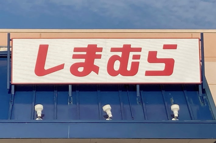 Sign with bold Japanese characters above a storefront entrance, under a blue sky