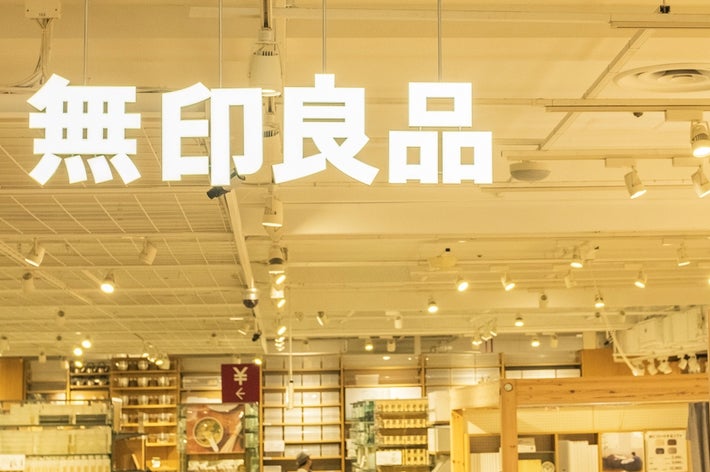 People shopping inside a well-lit Muji store with various products displayed on shelves