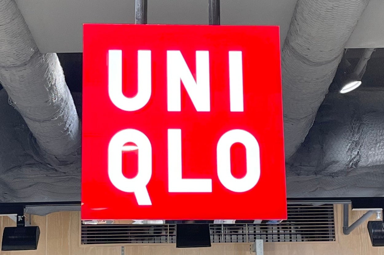 Red Uniqlo sign hangs inside a store; merchandise and price tags visible below