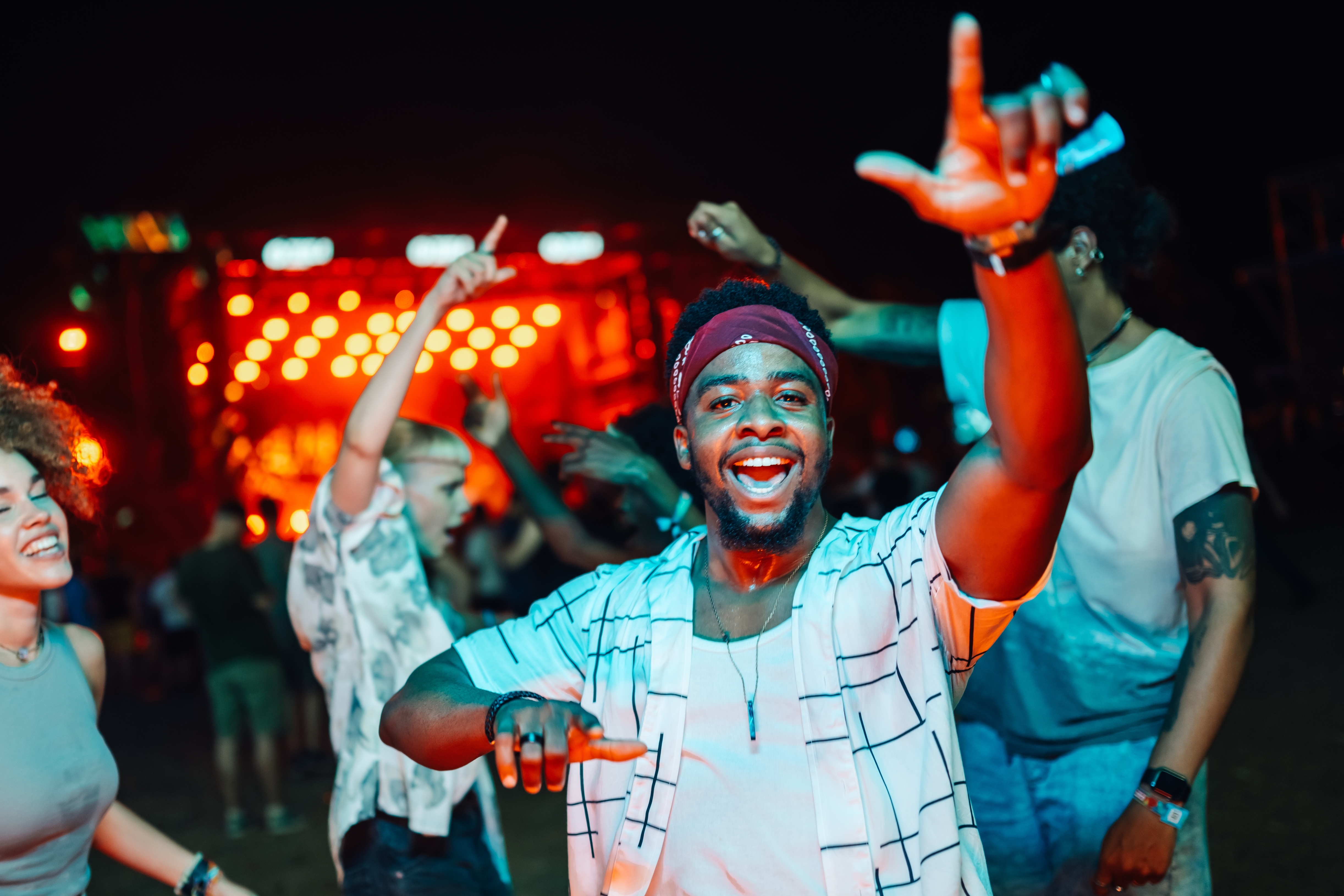 Person enjoys a lively music festival, surrounded by dancing people and bright stage lights