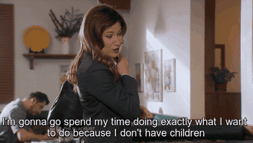 A woman with long hair and a bag, standing indoors, says, "I'm gonna go spend my time doing exactly what I want to do because I don't have children."