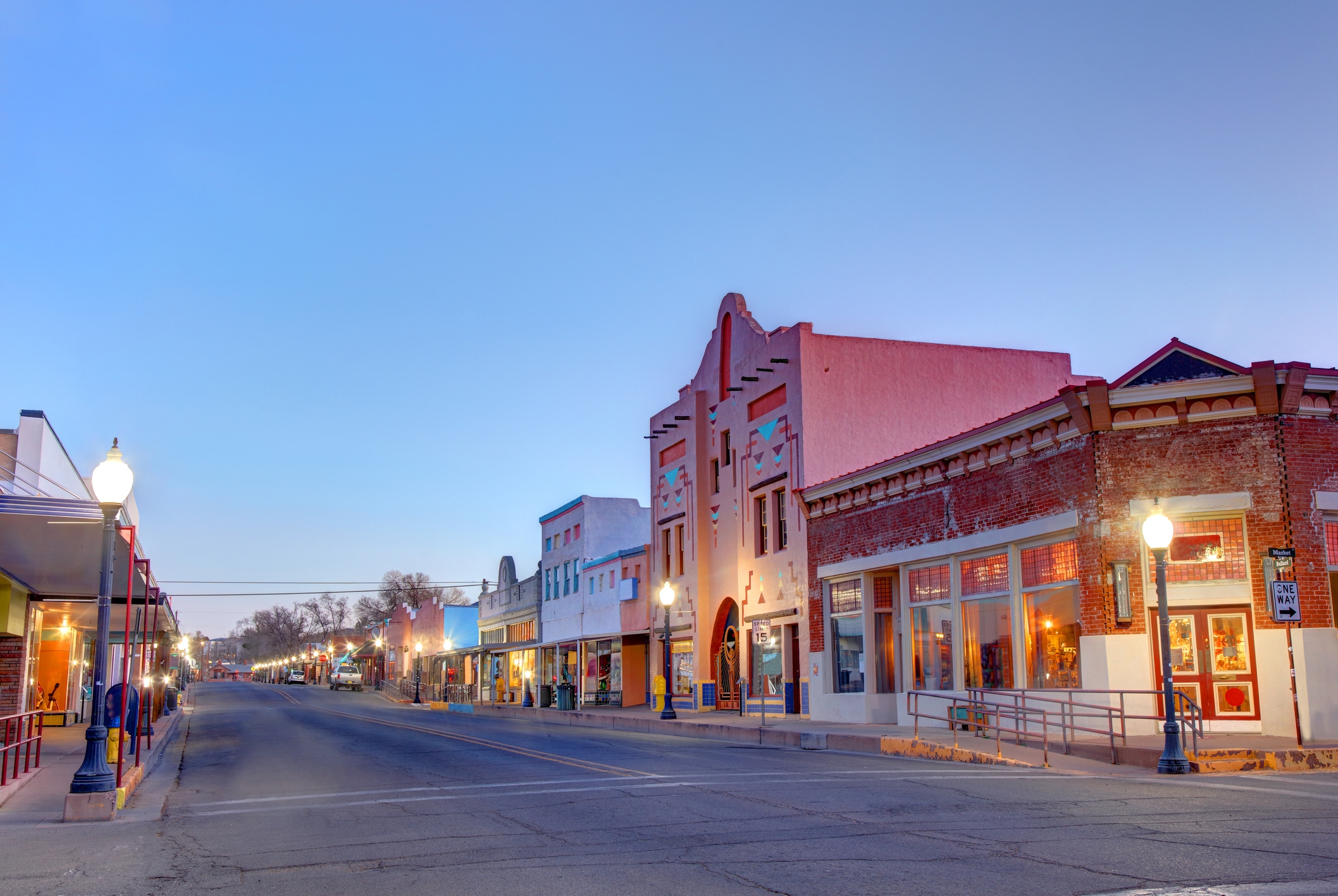 A quiet, early morning view of a small-town main street lined with vintage-style buildings and street lamps