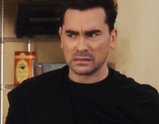Person in a black shirt appears displeased, squinting and grimacing, with the hashtag #SchittsCreek above