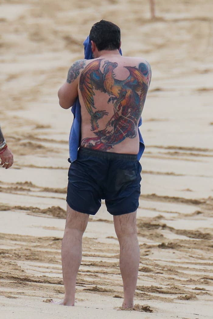 Ben Affleck on a beach with large back tattoo featuring a multi-colored phoenix