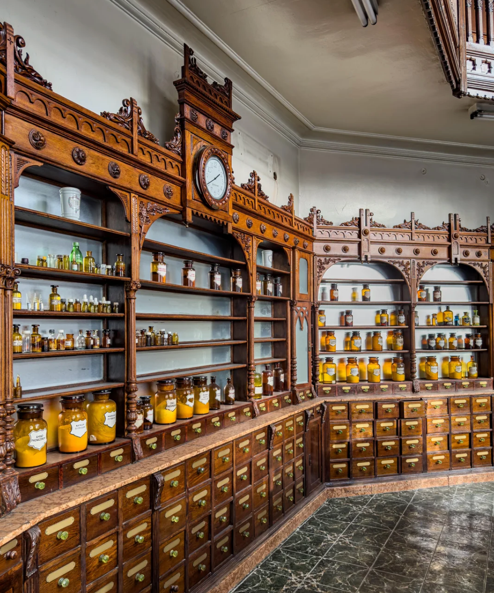 An ornate, vintage apothecary with wooden cabinets filled with labeled jars and bottles, featuring intricate designs and a central clock on the shelf
