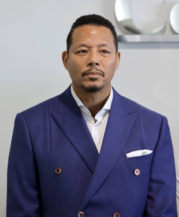 Terrence Howard in a stylish suit with a white pocket square stands against a neutral background