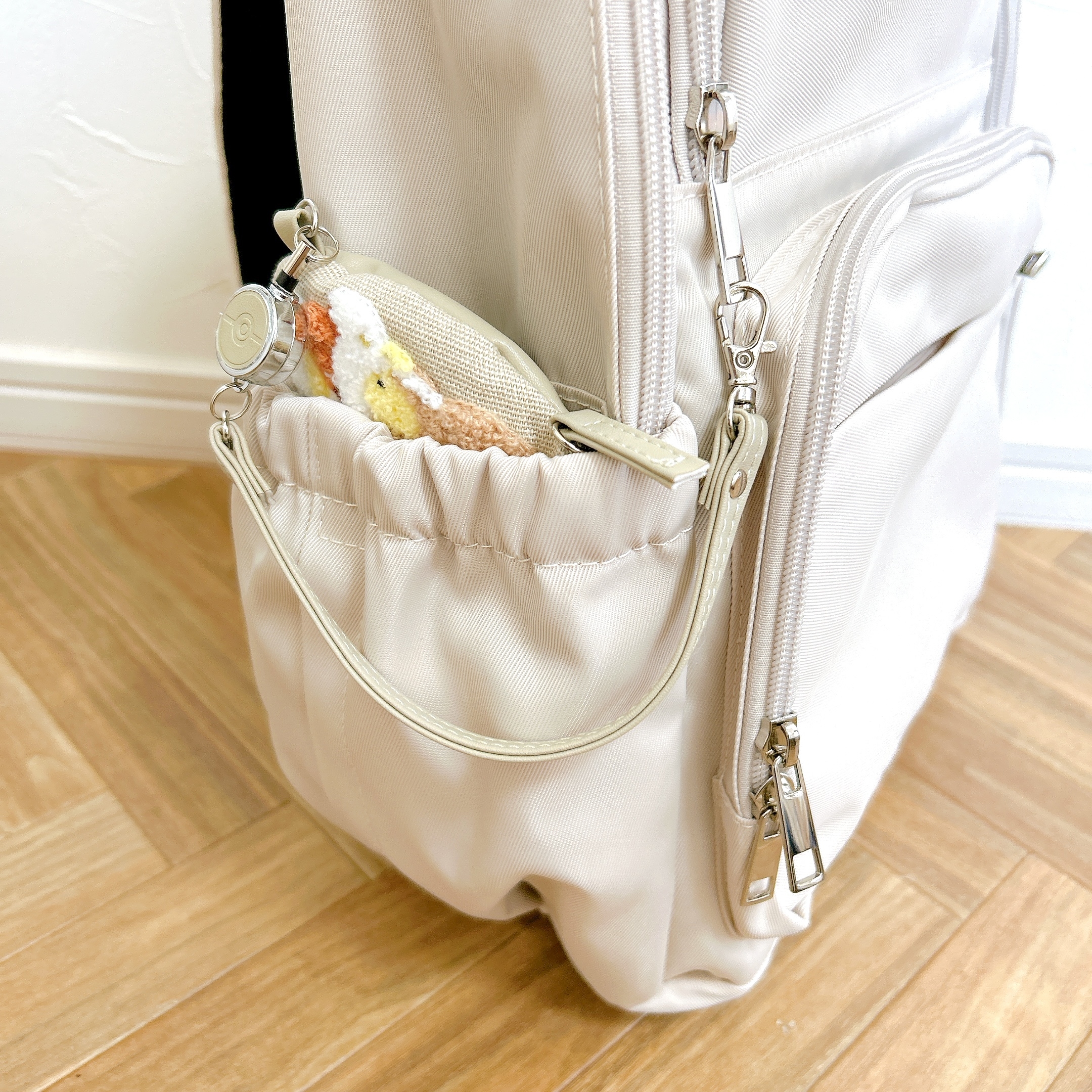 リュックのサイドポケットに小物ケースが見える。ポケットにはファスナーがあり、テクスチャーが柔らかそう。