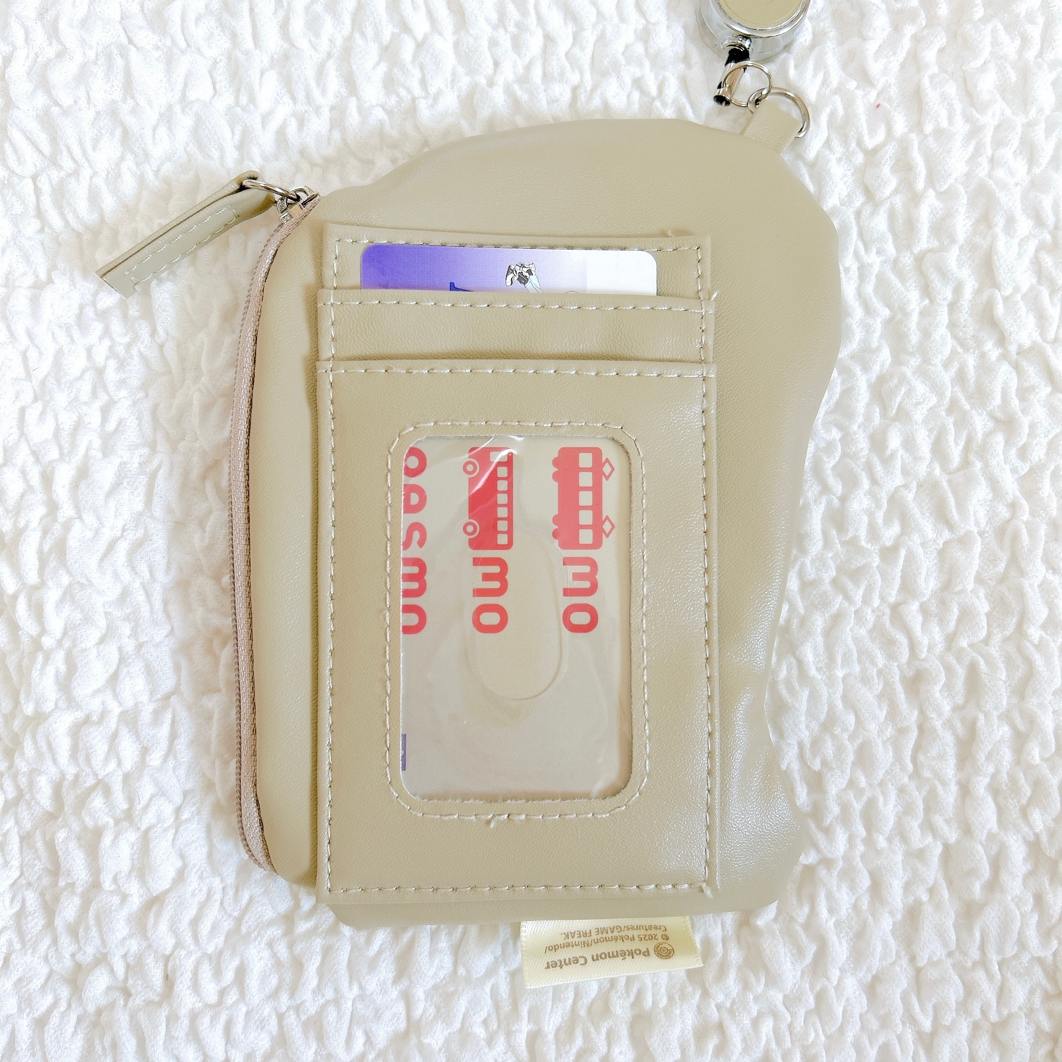 薄い革のカードホルダーに複数のカードが見える。表には窓付きポケットがあり、ドコモのカードが見えている。