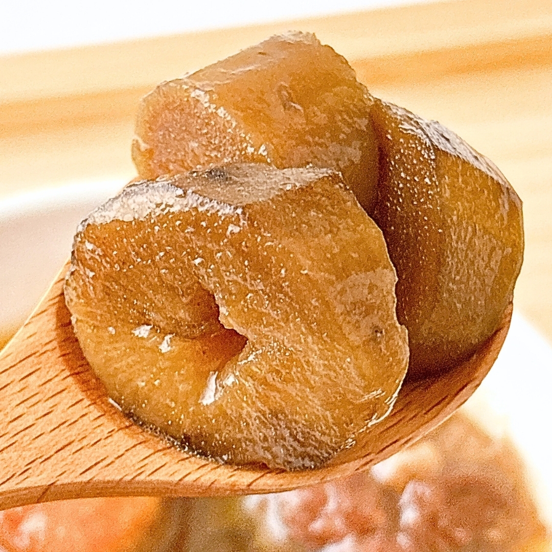 木のスプーンで持ち上げられた大根の煮物。