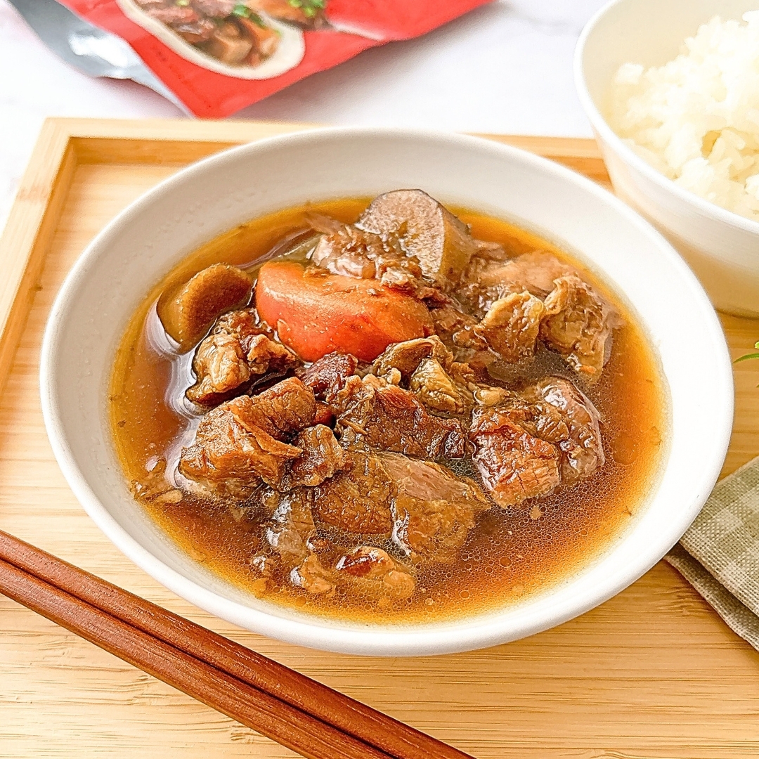 肉と野菜が煮込まれたカレー風の料理が白い皿に盛られている。隣にご飯の小鉢が置かれている。