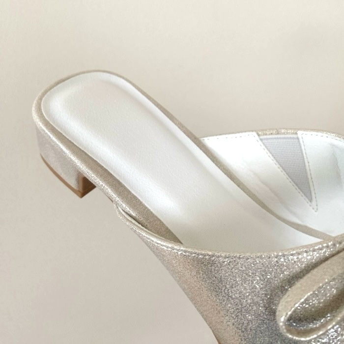 A single elegant slide sandal with a low block heel on a neutral background