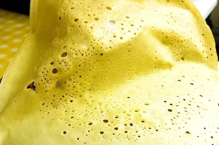 クレープが熱い皿の上で焼けている様子。焦げ目が付いた生地に小さな気泡が見える。