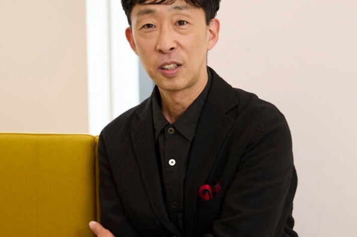 男性がスーツを着て、椅子にもたれ掛かっている。温かく落ち着いた雰囲気。