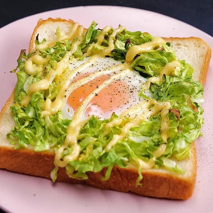 食パンの上に半熟卵と刻んだレタス、マヨネーズがトッピングされた料理。