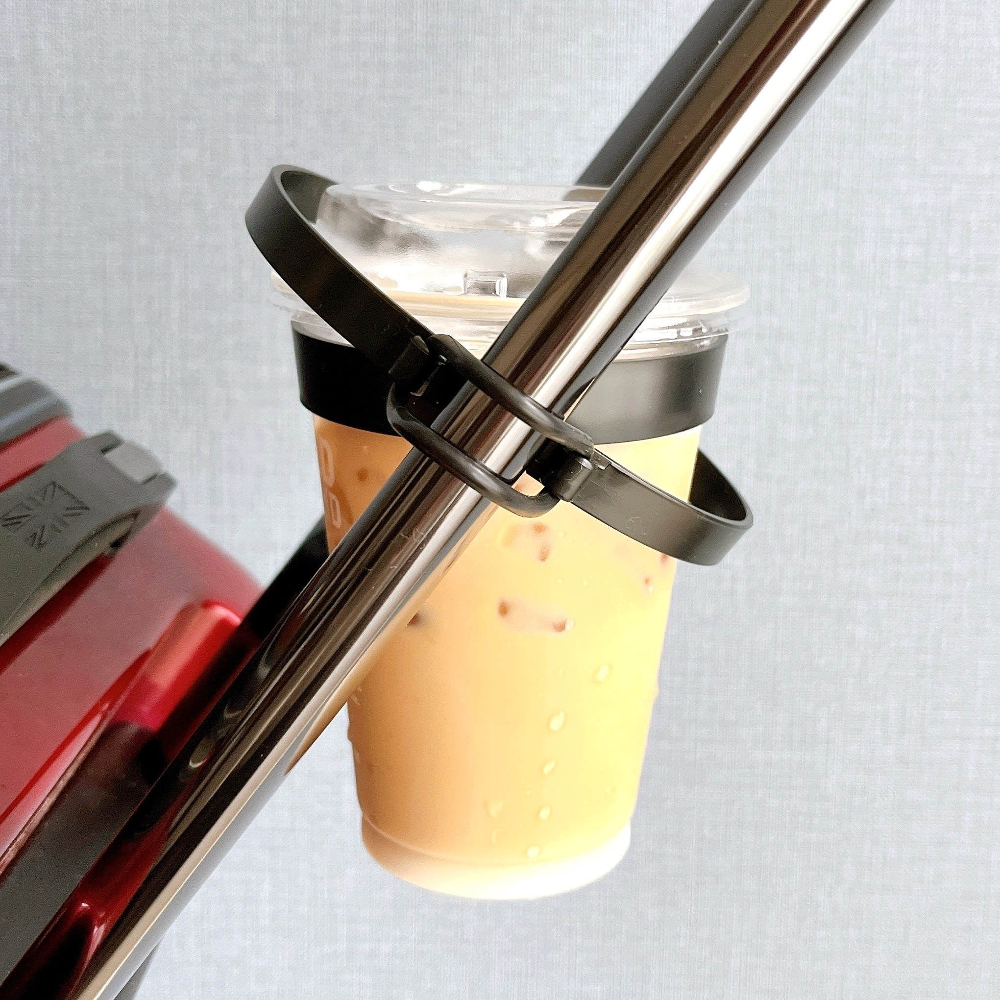 透明な蓋付きのアイスコーヒーが、独自のホルダーで自転車のハンドルに固定されている。