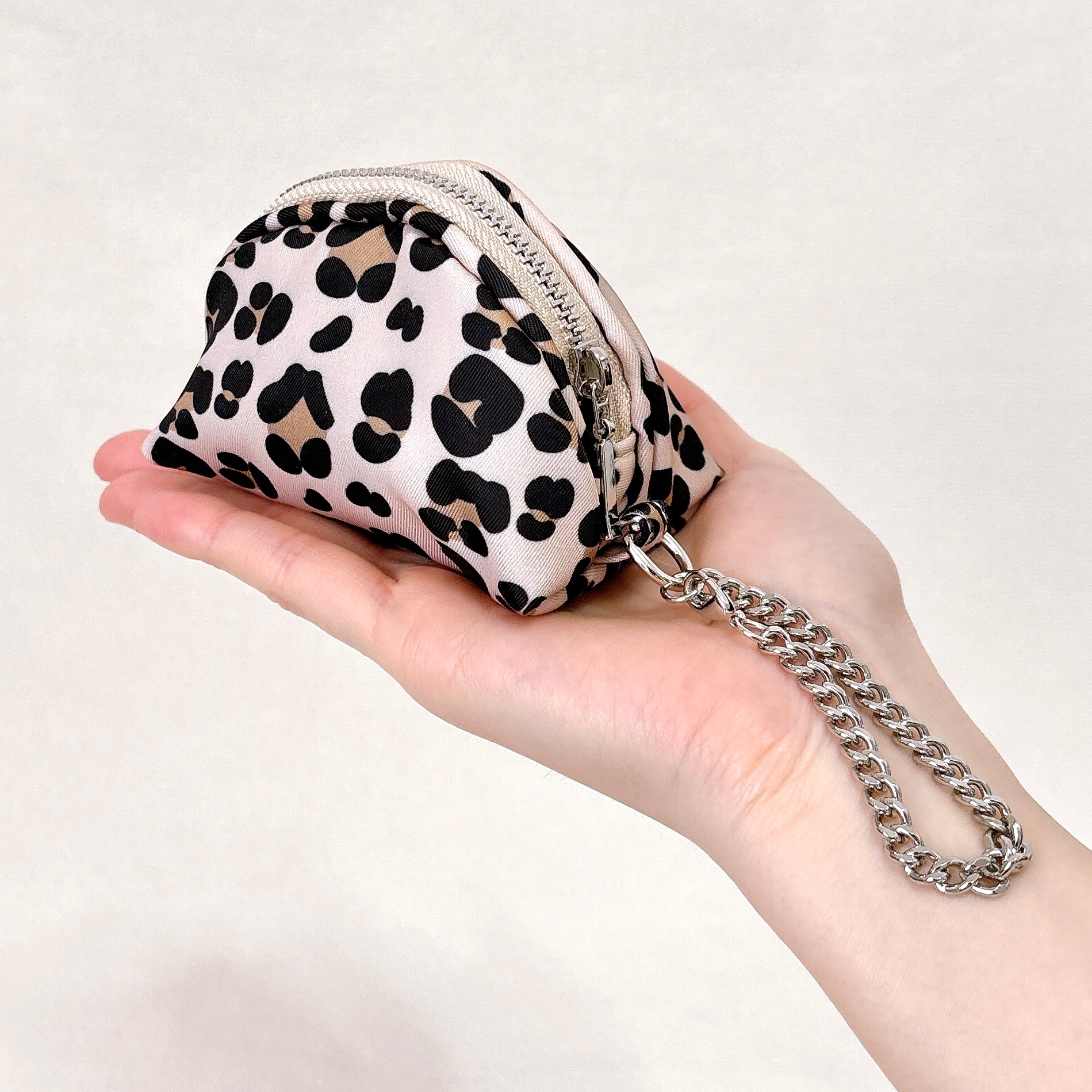 手に持たれたレオパード柄の小さなポーチ。チェーン付き。