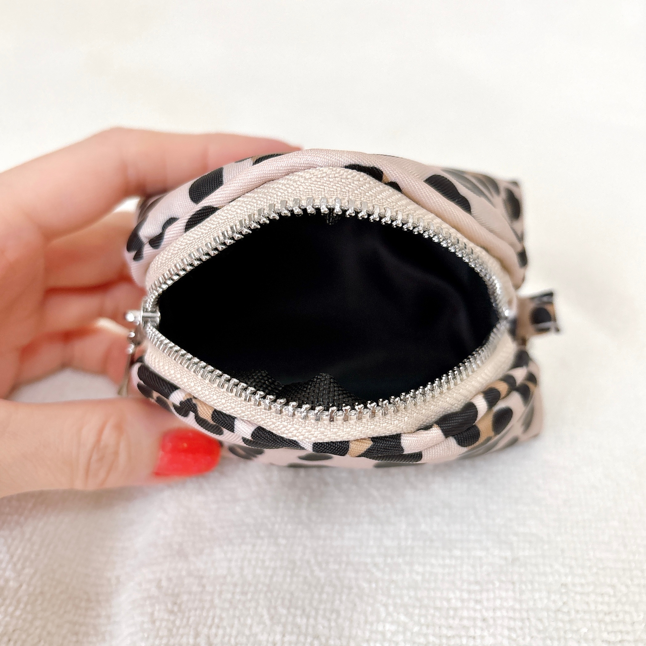 手に持たれた開いた小さなドット柄ポーチのクローズアップ。