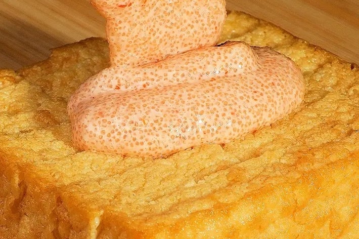 厚揚げの上に明太子ソースがかけられている料理のクローズアップ。