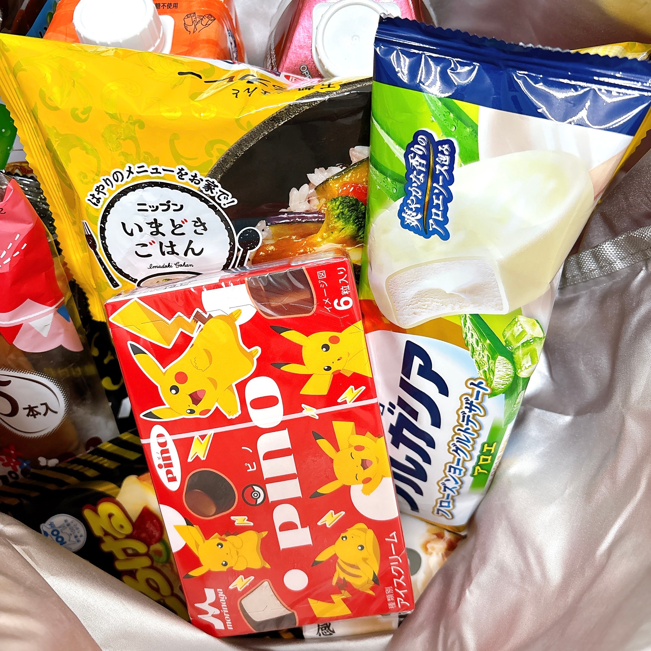 袋に詰まった日本のお菓子やアイスのパッケージ。ポケモンが印刷された箱もあり、バラエティ豊かなスナックが並ぶ。