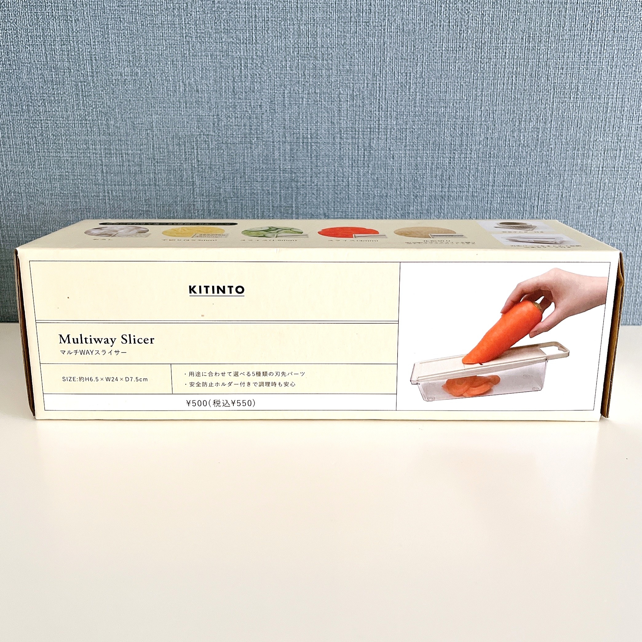 マルチウェイスライサーの箱の画像。片手でニンジンをスライサーにセットしている写真が描かれている。