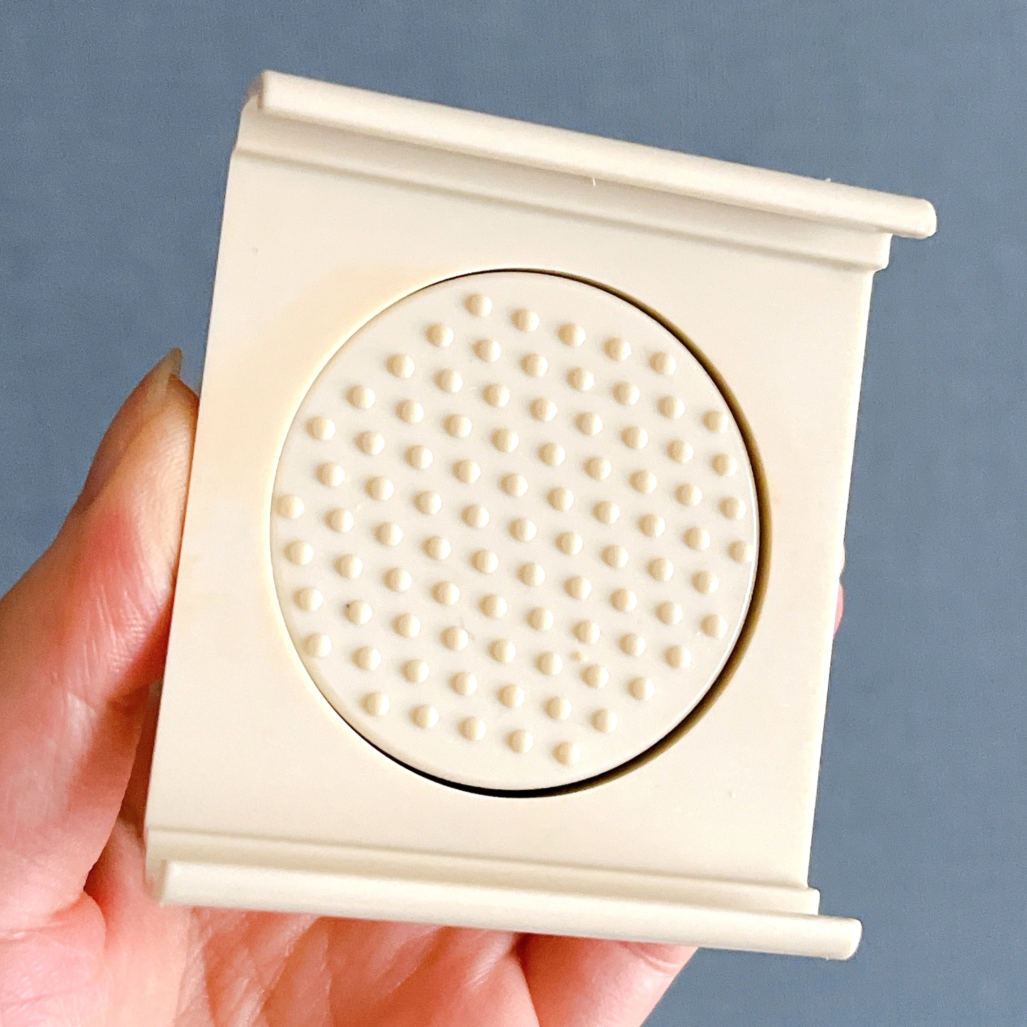 滑り止め加工が施された白いプラスチック製の丸い物体を手に持っている。