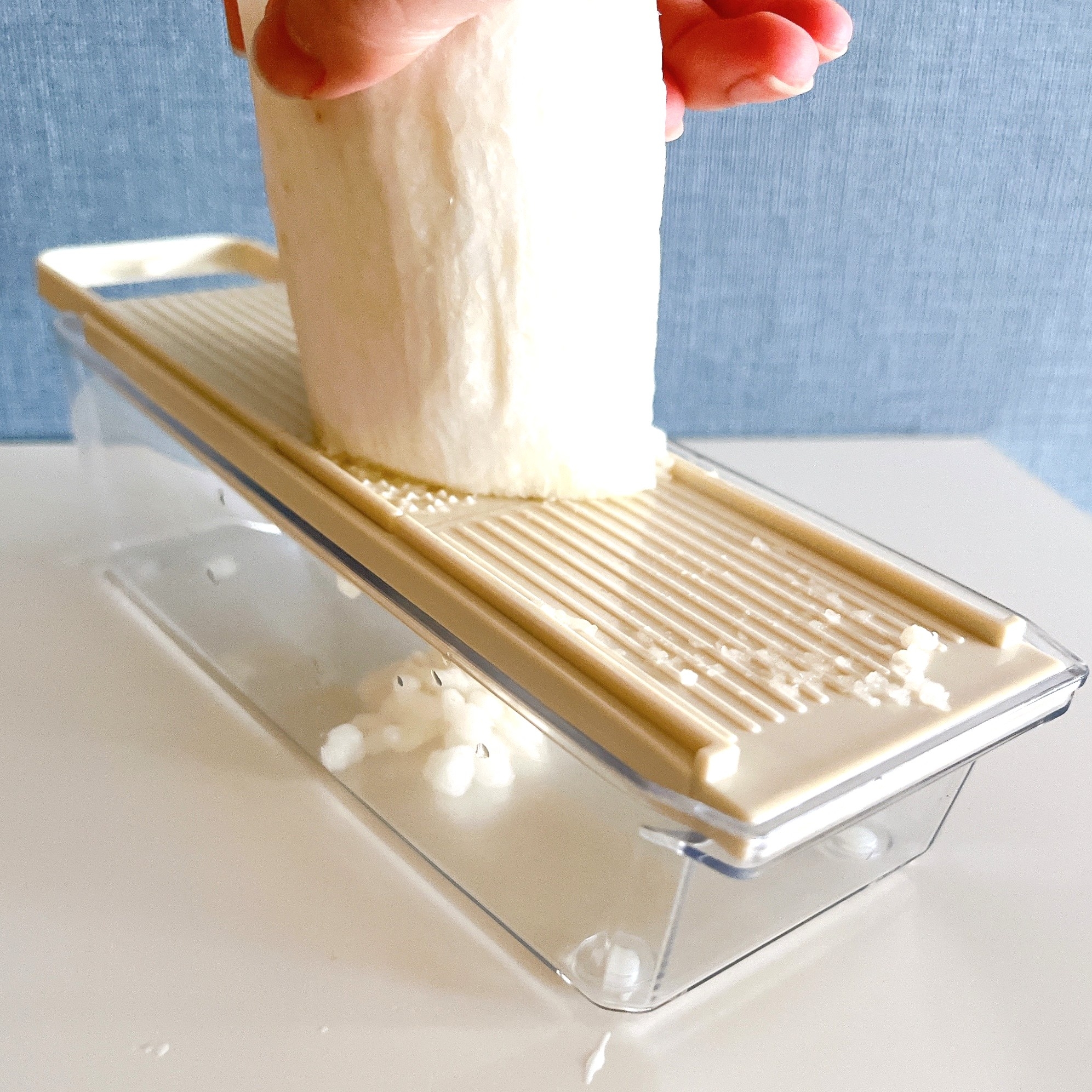 大根をスライサーでおろしている様子。スライサーの下におろされた大根が溜まっている。