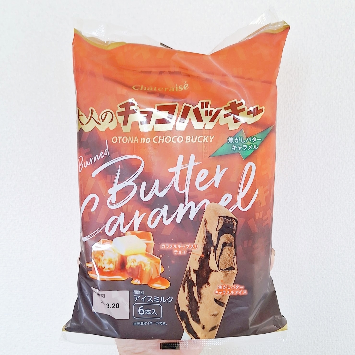 大人のチョコバッキー バターキャラメル味のアイスクリーム6本入りパッケージ。手で持たれている。