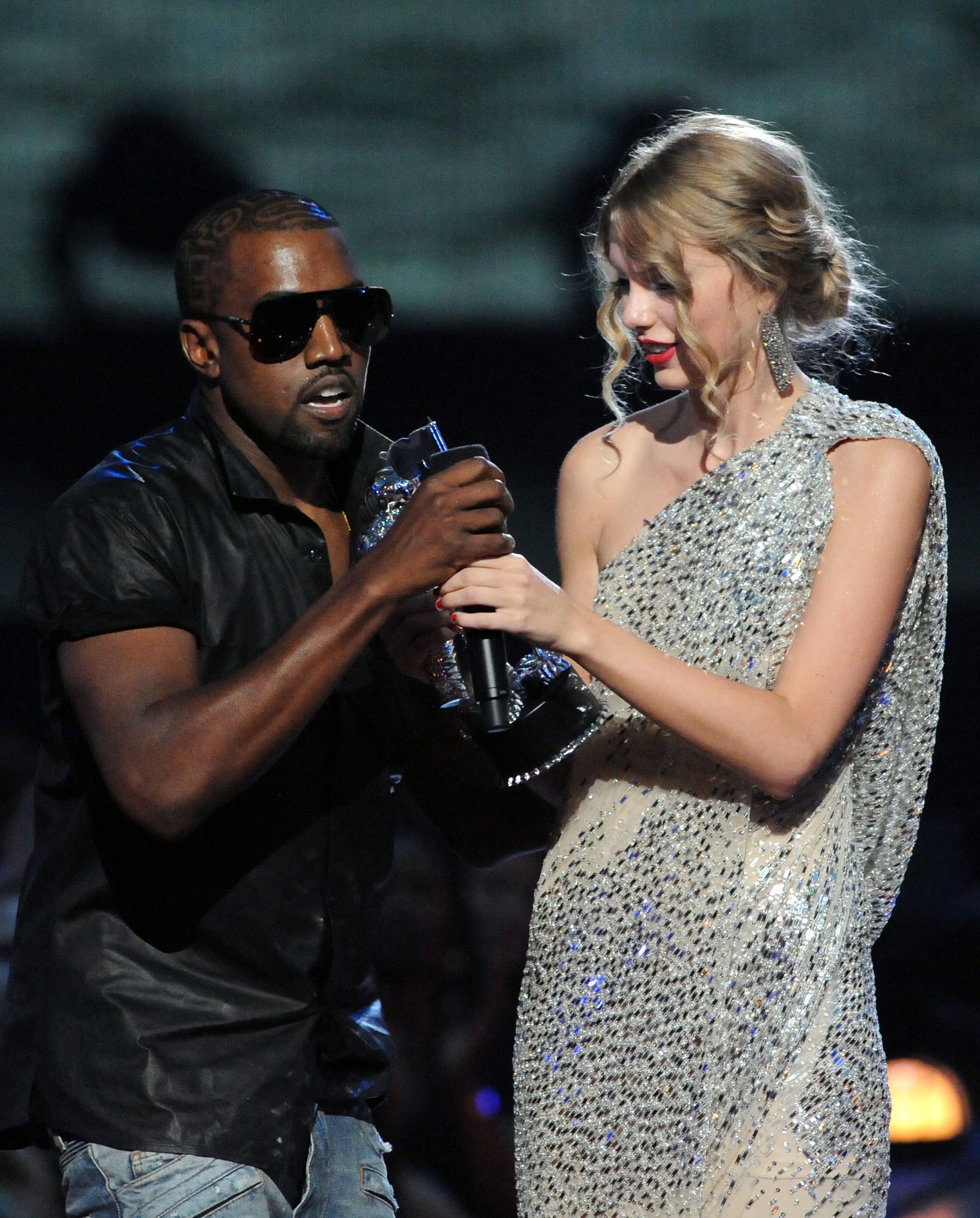 Kanye West onstage while Taylor Swift accepts an award