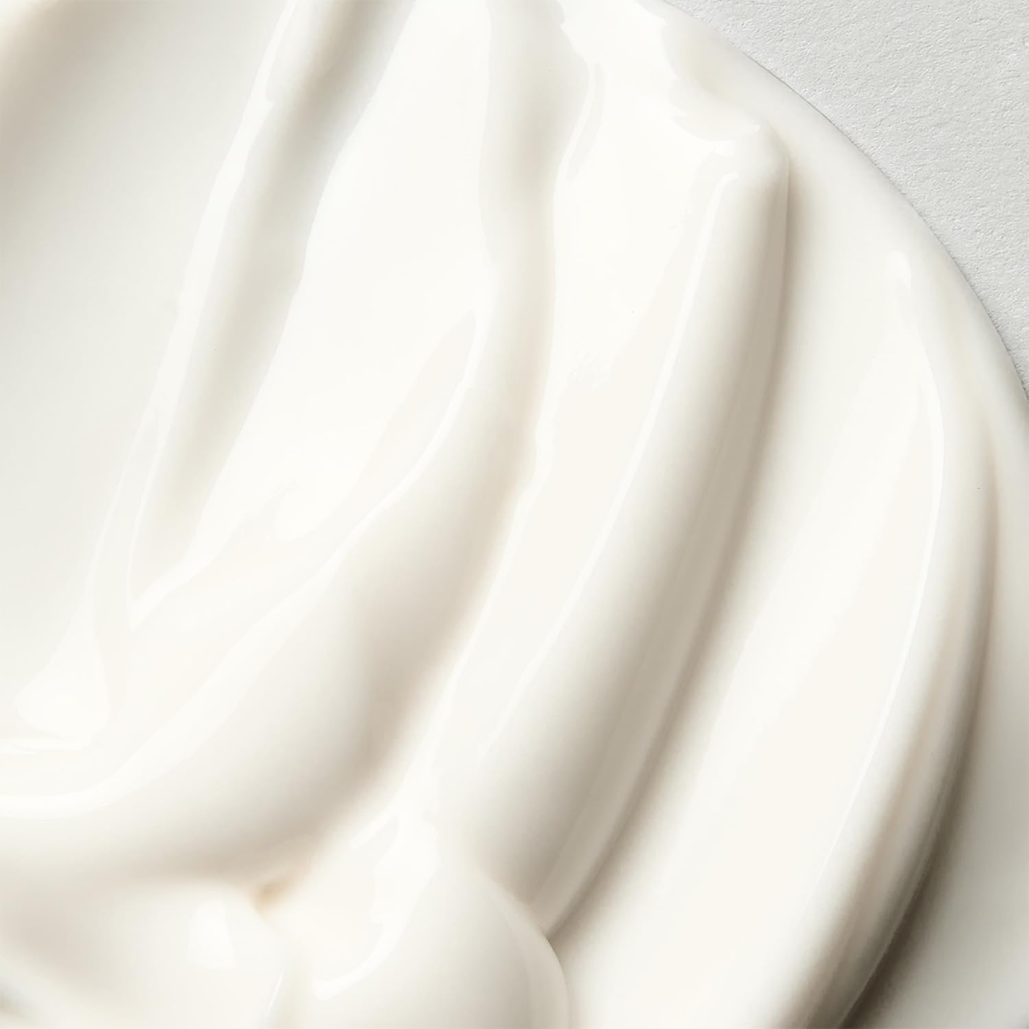 Close-up of creamy skincare product swirled on a smooth surface, suggesting a rich and moisturizing texture. Suitable for a shopping article
