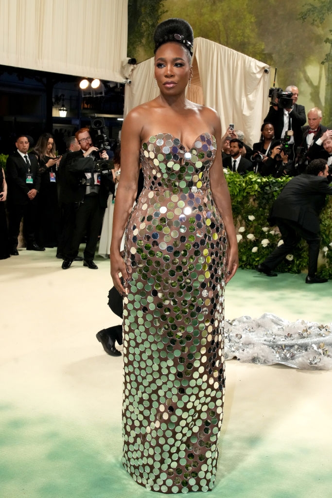 Venus in a strapless sheer gown covered in small mirror disks