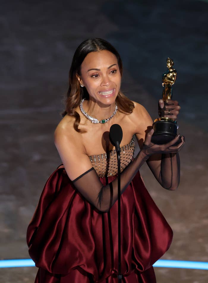 Zoe Saldaña holding an Oscar on stage